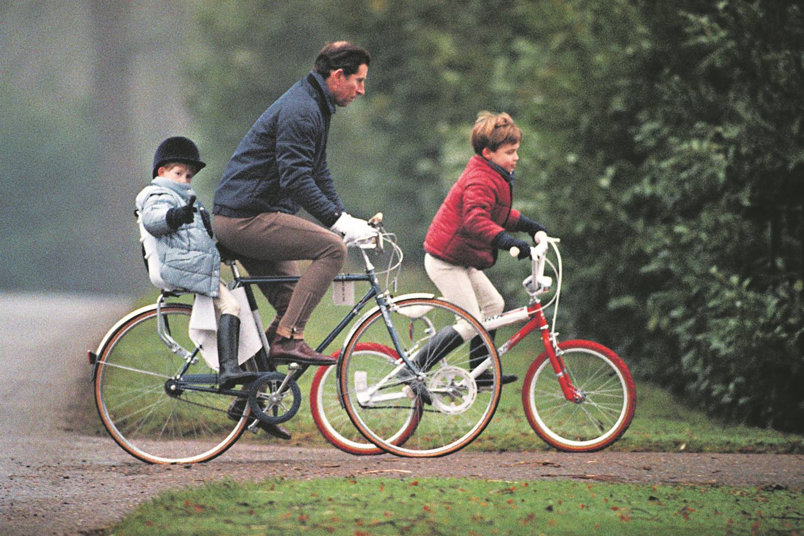 Die klein prins Harry ry agterop prins Charles se fiets saam met prins William op die Sandringham-landgoed in Norfolk.  Foto’s: Getty Images