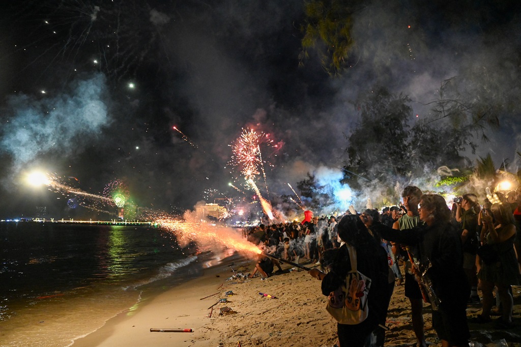 People firing fireworks at a beach