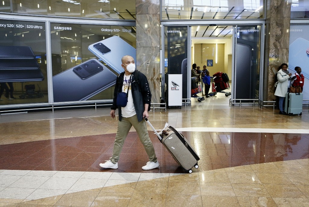 A passenger wearing a protective face mask walks, after arriving from Shenzhen in China, at the OR Tambo International Airport in Johannesburg. 