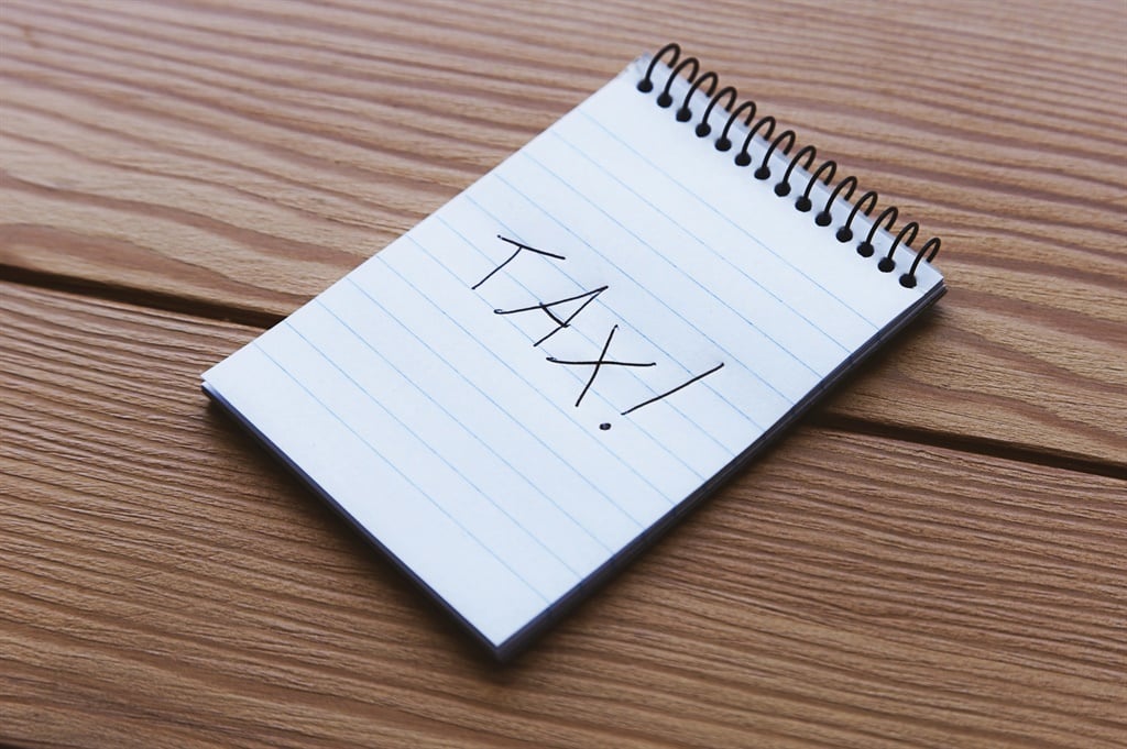 A notepad with the words, TAX! written on it. Tax 
