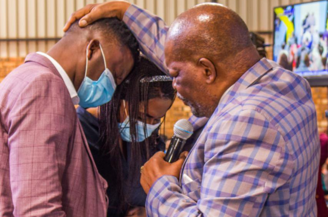 Dr SD Gumbi prays for Bishop Makamu and his wife during a church service. 