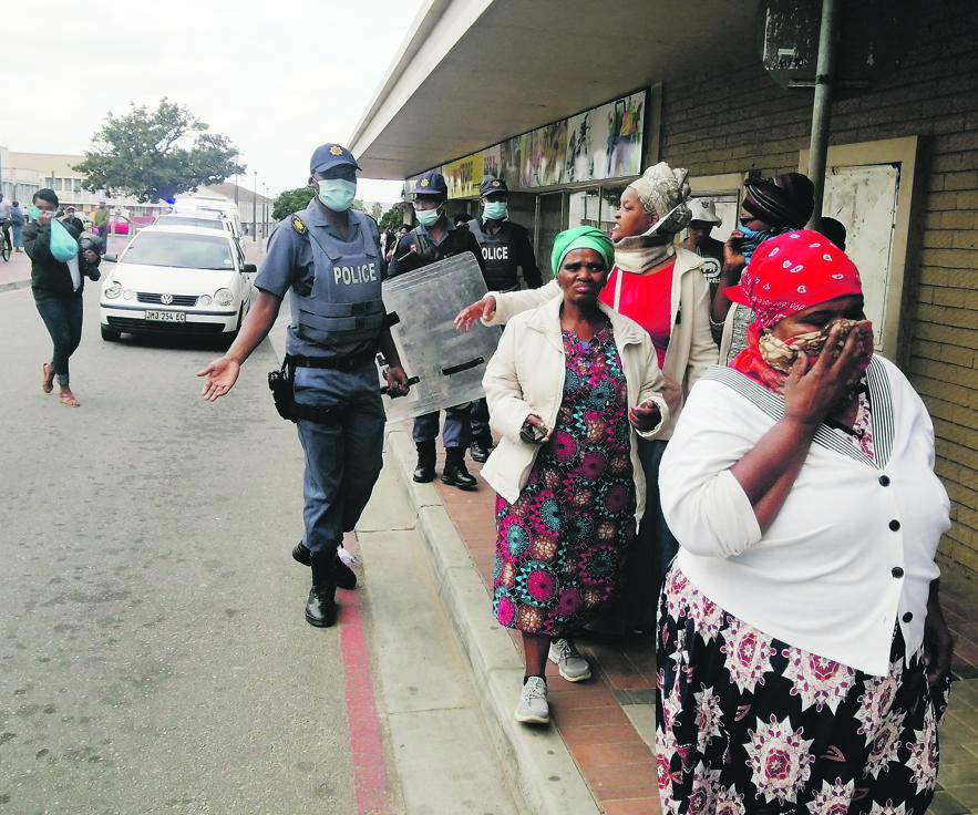Cops escort people out of the Sassa offices in Uitenhage. Photo by Mkhuseli Sizani
