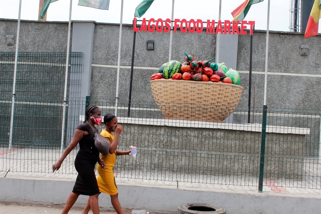 Girls wearing facemasks walk past the fence of Mile 12 Food Market in Lagos, Nigeria on Monday, May, 4 2020. Picture: Adekunle Ajayi/NurPhoto via Getty Images)
