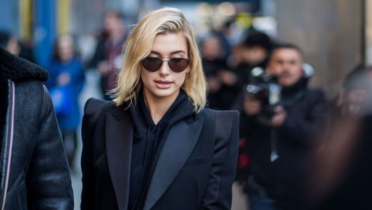 Model Hailey Bieber  wearing black blazer with strong shoulder line and hoodie. (Photo by Christian Vierig/Getty Images)
