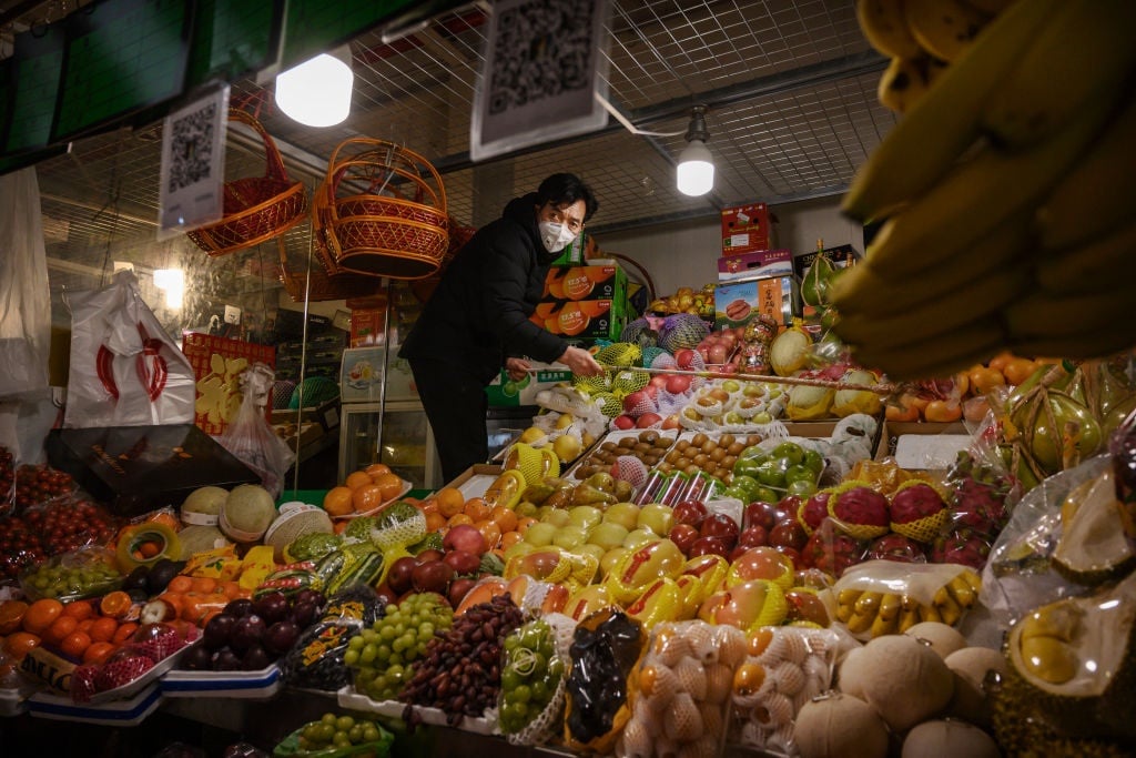 A fruit vendor arranges his stock as he wears a protective mask at a local market in Beijing, China. 