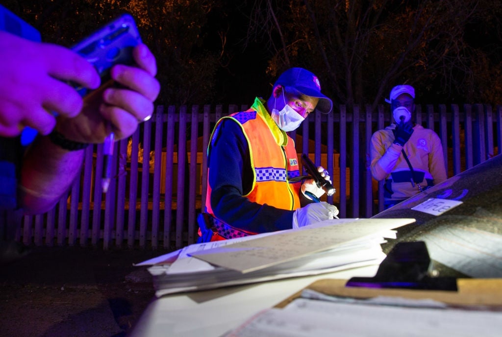 A law enforcement officer writes out a fine after pulling over a driver at a roadblock in cape Town to ensure that non-essential vehicles are not on the road. (Roger Sedres, Gallo Images via Getty Images)
