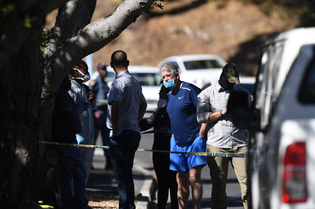 William Booth (in blue shorts) speaks with police officials outside his Higgovale home shortly after the attempt on his life on the morning of 9 April. Photo - Jaco Marais