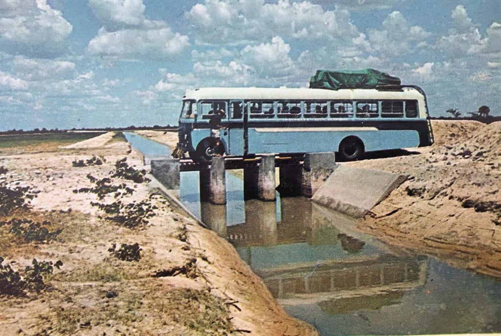 Die seweton-Leyland-bus (gehuur by die Hoërskool J.J. Du Preez in Kaapstad) ry versigtig oor ’n smal brug in Namibië. Die water in die kanaal kom van die Kunenerivier
