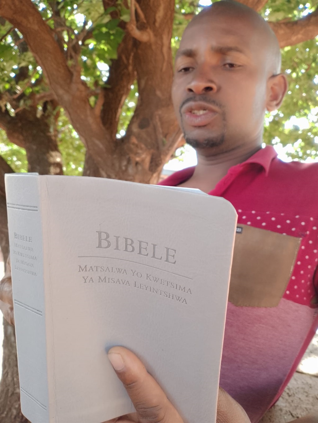 Albert Mpangase reading his bible. Photo by Sammy Moretsi