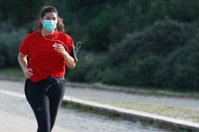 A woman running at the Parque das NaÃ§Ãµes wearing a mask, Lisbon, Portugal.