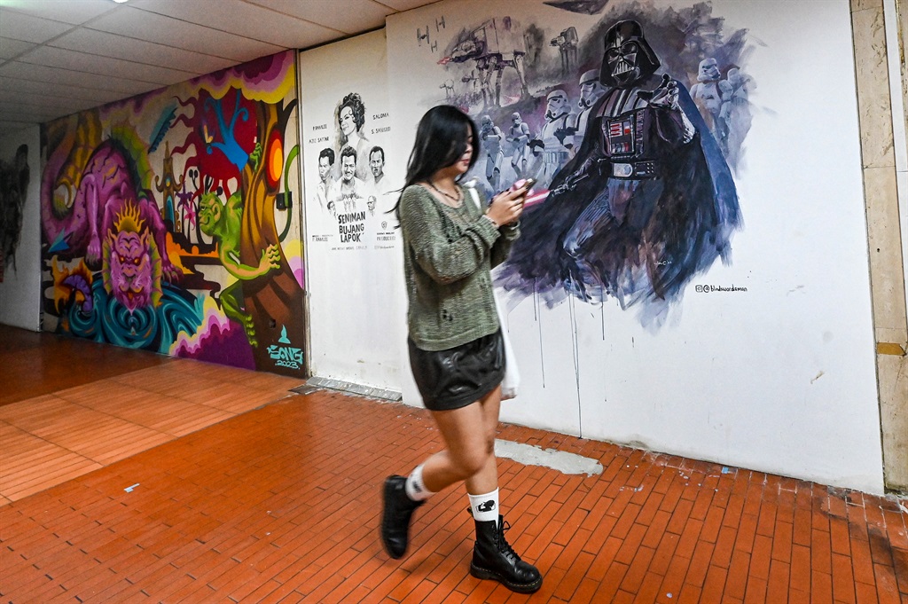 A woman walks past murals at the Peace Centre, an 