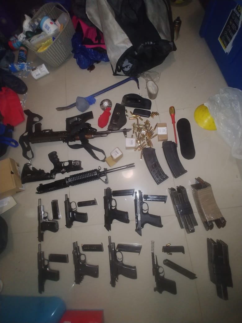 Police nabbed one of the most wanted suspects and recovered a bag with nine (9) pistols and two (2) rifles and magazines with live ammunition and a white Mercedes Benz AMG suspected to be hijacked was also found in the yard. Photos Supplied