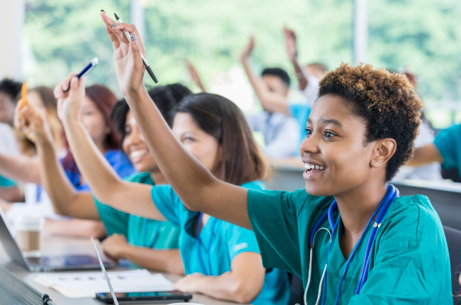 Medical students raising their hands during class (PHOTO: SDI Productions/Getty Images)