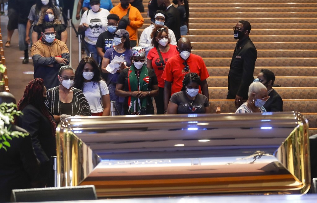 Mourners wait in line to pass by the casket of Geo