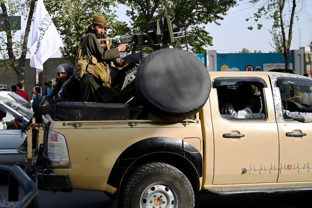Taliban fighters travel with weapons mounted on a 