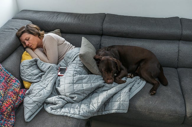 Woman asleep on the sofa with her dog