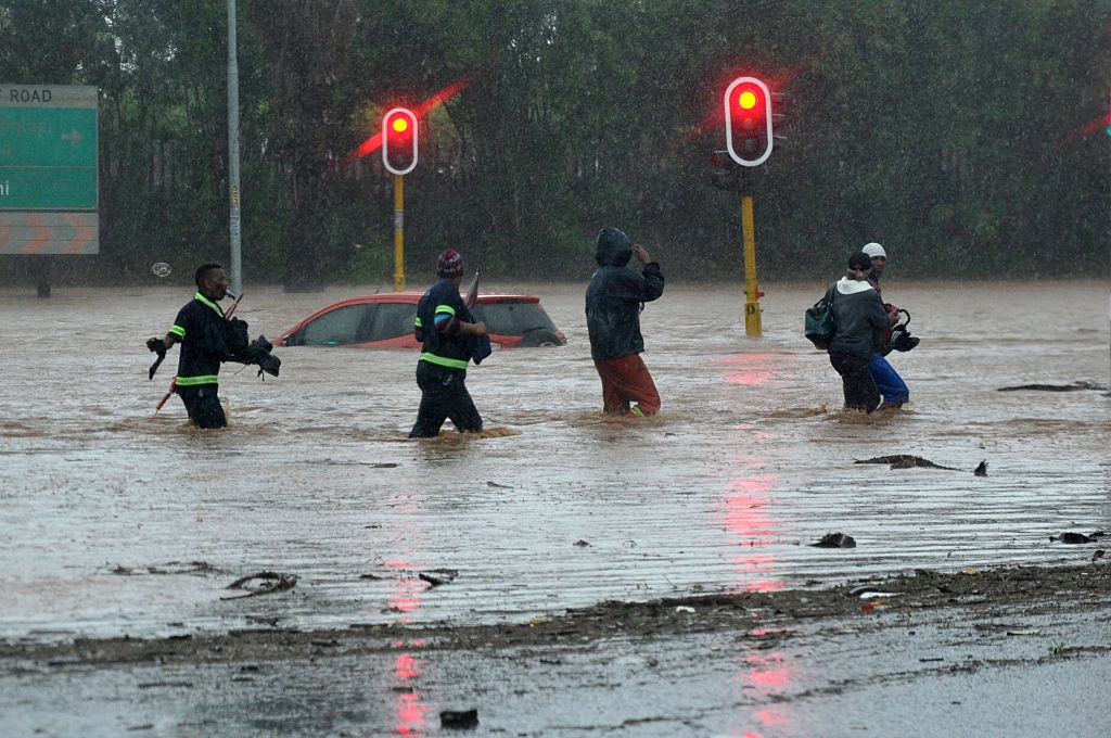 A car floats on a Durban road as people wade through water during severe floods in October 2017. 