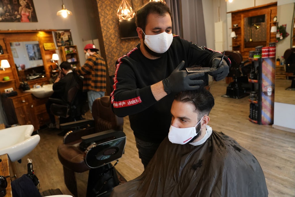 Barbers cut the hair of customers as all of them wear protective face masks in Berlin, Germany. 