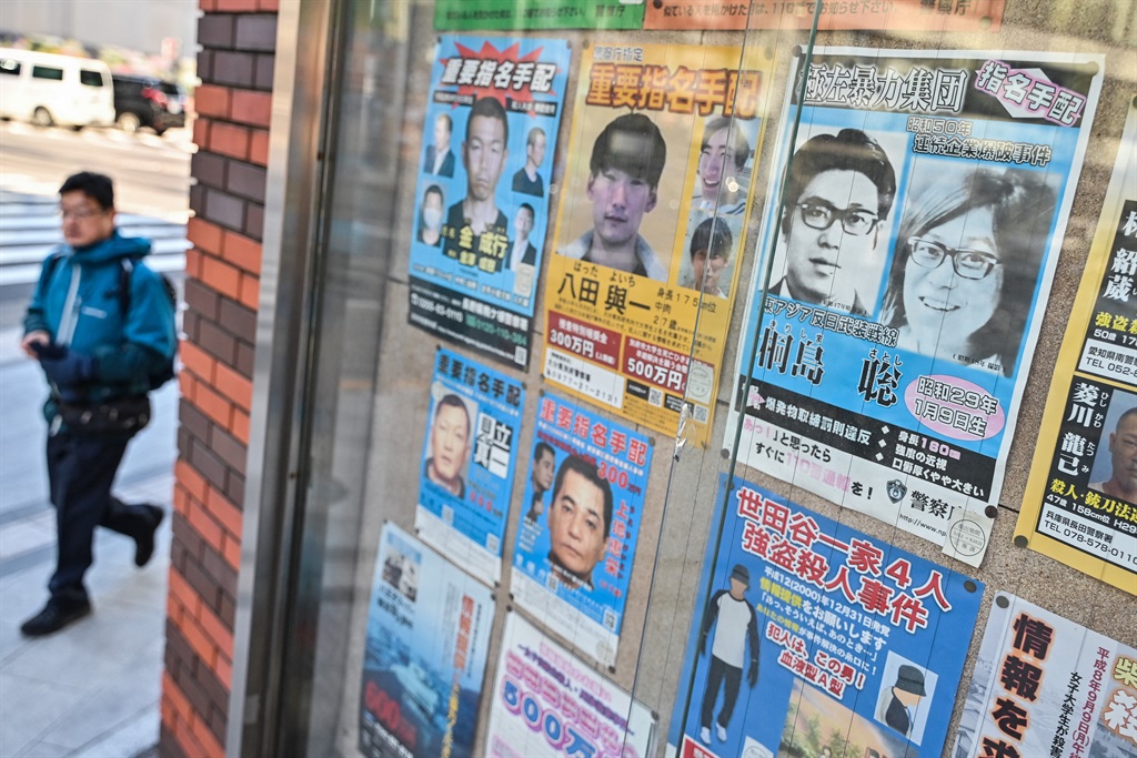 A man walks past a case showing many of Japan's most wanted criminals, including a poster of Satoshi Kirishima (top R), who was a member of the East Asia Anti-Japan Armed Front - a radical leftist organisation responsible for bombing attacks in Japan's capital in the 1970s - outside a police box in Tokyo on 29 January 2024. Local media have reported on 29 January that the man believed to be Kirishima has died at a local hospital in Kanagawa prefecture near Tokyo only days after he was reportedly caught after almost 50 years on the run.