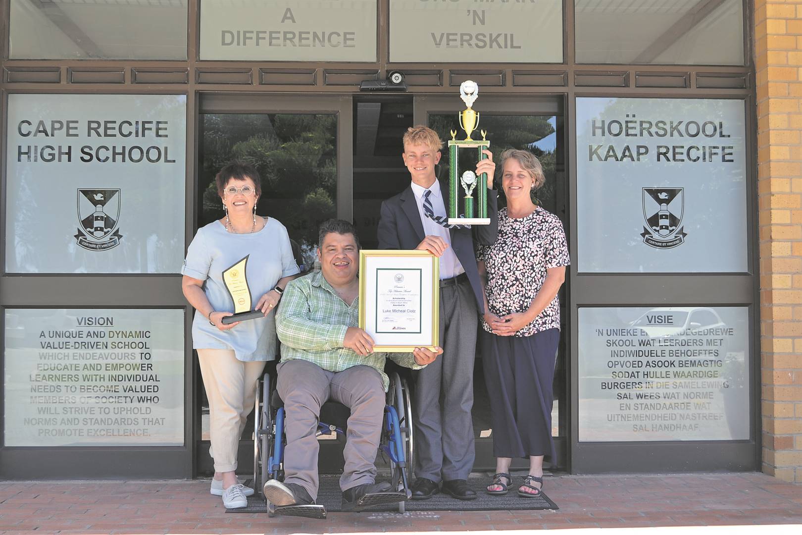 From left are Erica Maritz (principal), André van der Merwe (teacher), Luke and his mom, Beth Clotz. INSET: Luke Clotz wore his high school uniform for the last time, proudly holding his achievements, and looking forward to the future.                         