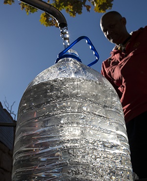A man collects drinking water from taps that are fed by a spring in Newlands, in Cape Town. (Photo: Rodger Bosch, AFP)