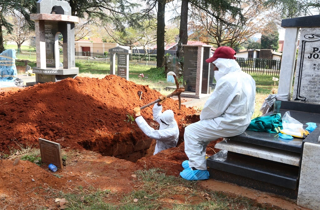 Workers in protective gear work at a cemetery. 