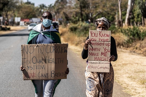 A man and a woman hold placards during an anti-corruption protest march along Borrowdale road in Zimbabwe. 