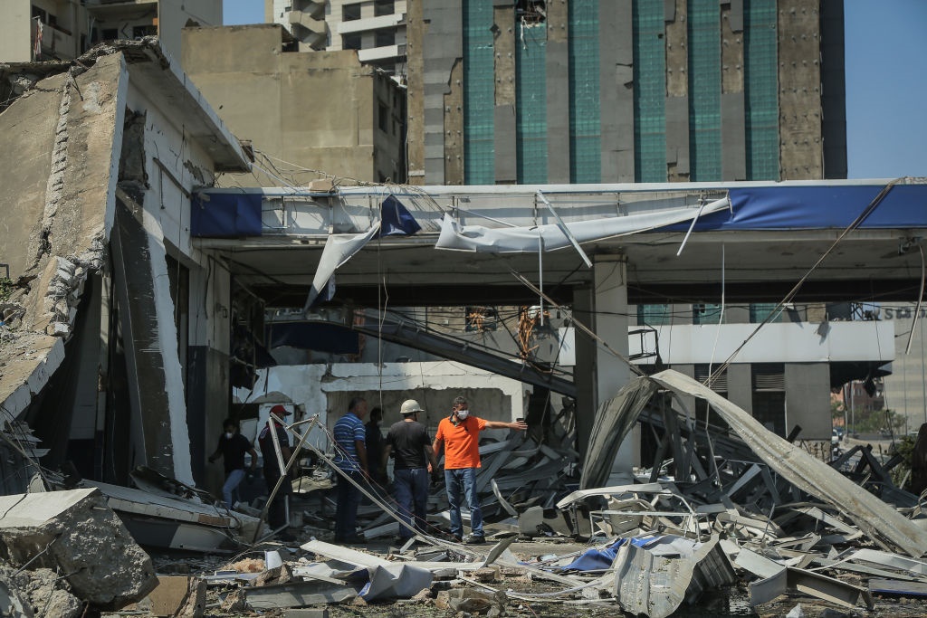 People inspect destruction outside a damaged building a day after a massive explosion in Beirut's port.