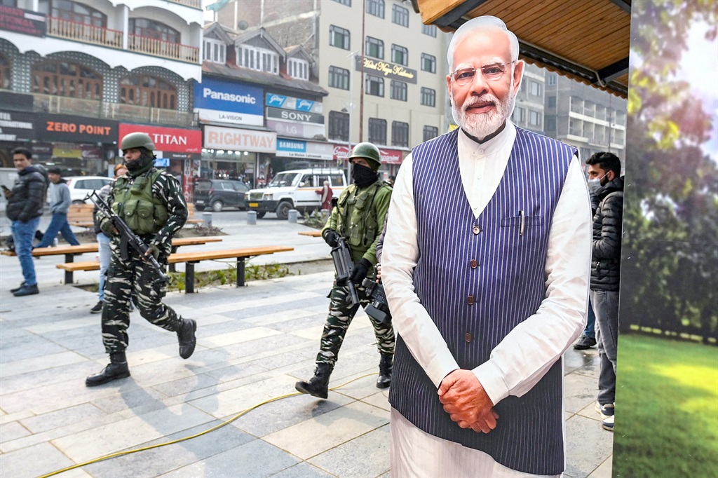 Indian paramilitary troopers patrol past a cut-out of Prime Minister Narendra Modi in Srinagar on 11 December, 2023, ahead of Supreme Courts verdict on Kashmir. (Photo by TAUSEEF MUSTAFA / AFP)