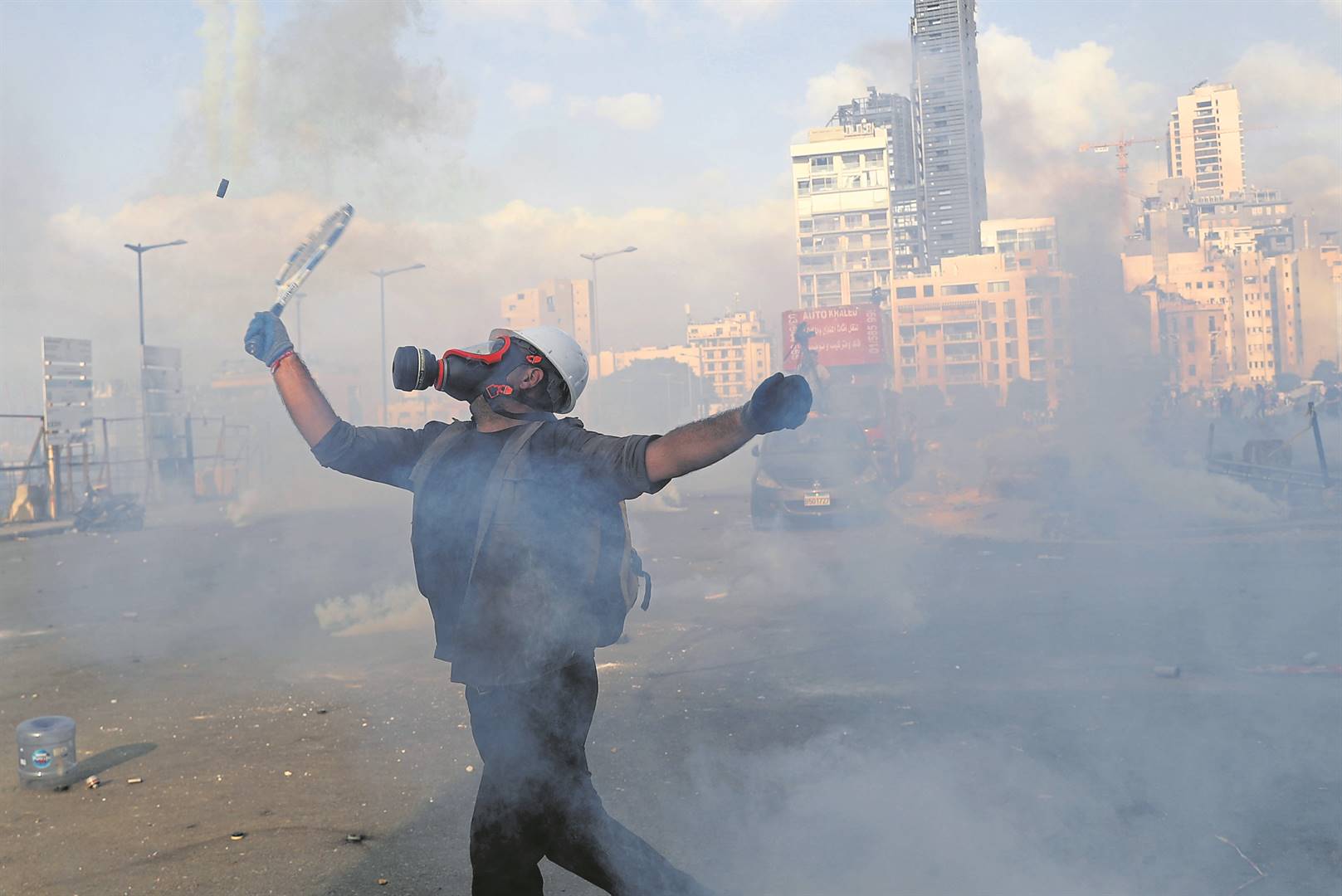 ’n Betoger slaan ’n traanrookhouer met ’n tennisraket terug na die onluspolisie in die oproer Saterdag in Beiroet. Foto: AP