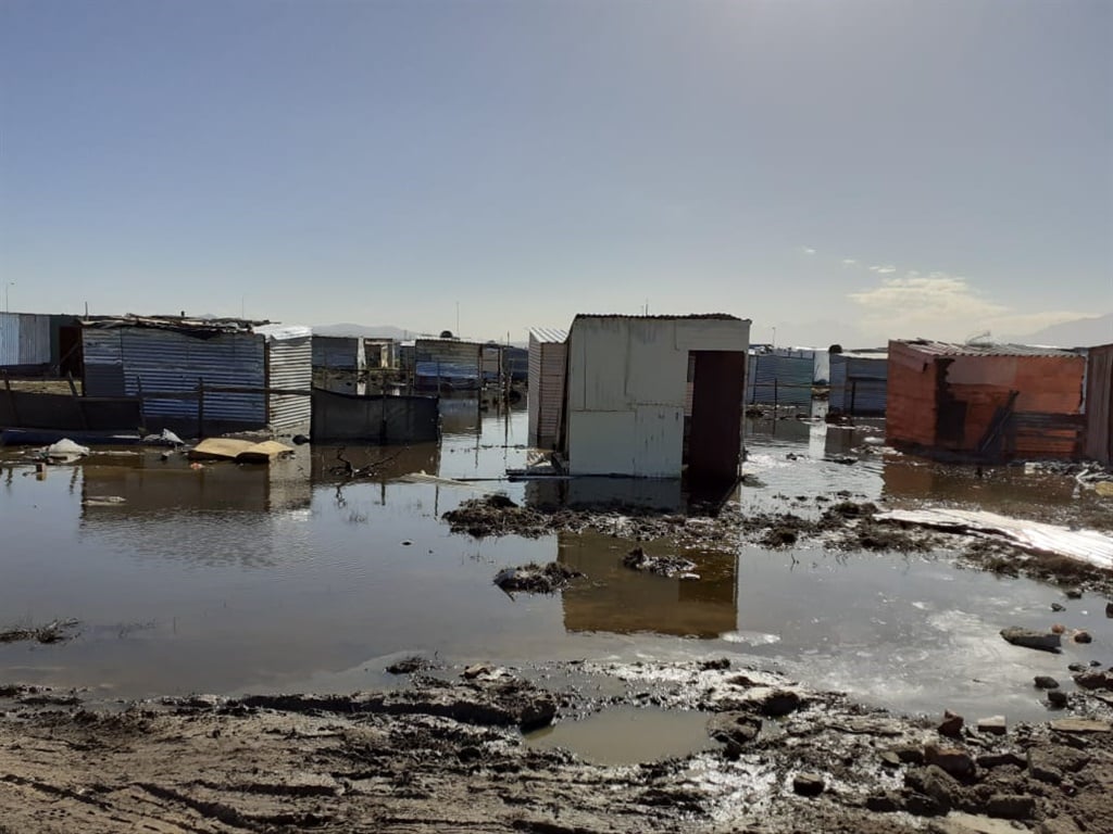Flooded shacks being moved by residents to dry ground. 