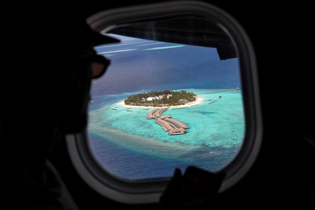 Traveller looking at a Maldivian island through a plane window.
