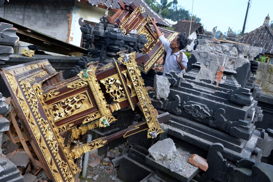 n Man tussen die beskadigde dele van 'n tempel ná 'n aardbewing wat die noordoorste van Bali getref het. Foto: Fikri Yusuf/ REUTERS.