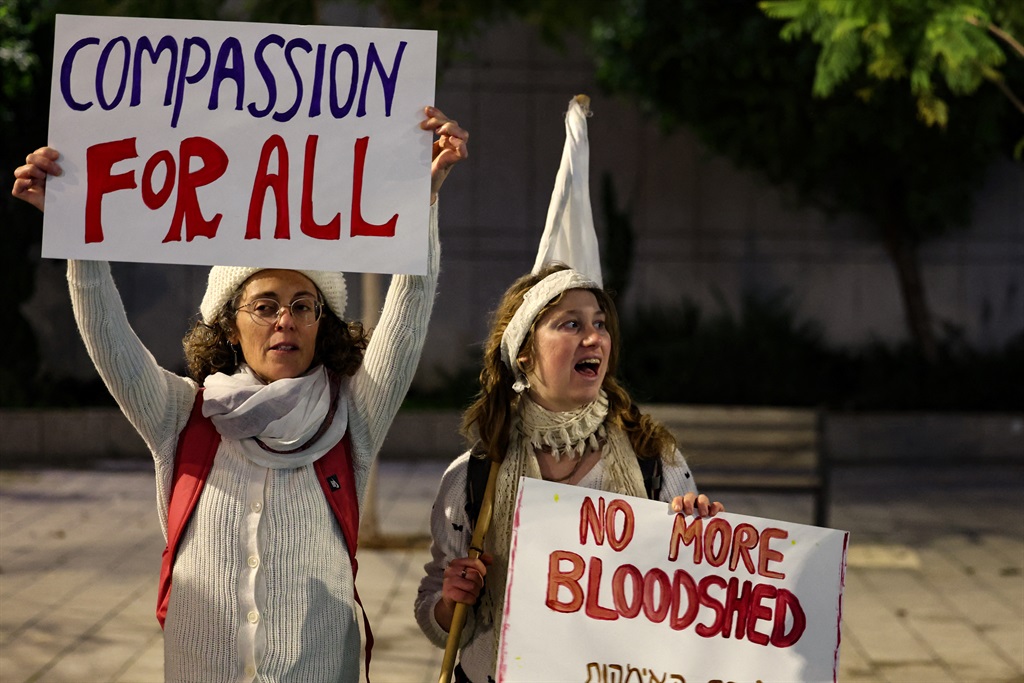 Israeli women raise placards bearing messages as t