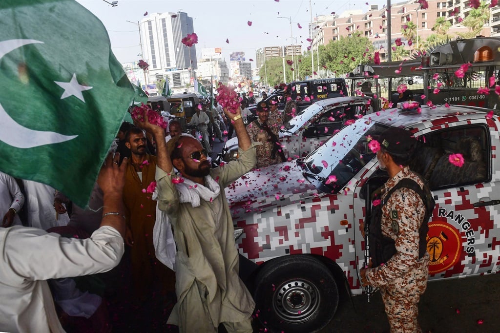 People shower rose petals on Pakistani soldiers during a May 2023 rally in support of the military. (Photo by Asif HASSAN / AFP)