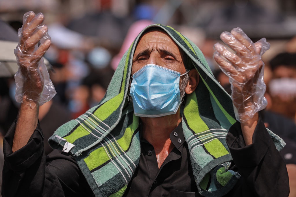 A Muslim wears a protective face mask and gloves as he performs the Friday prayers in Iran.