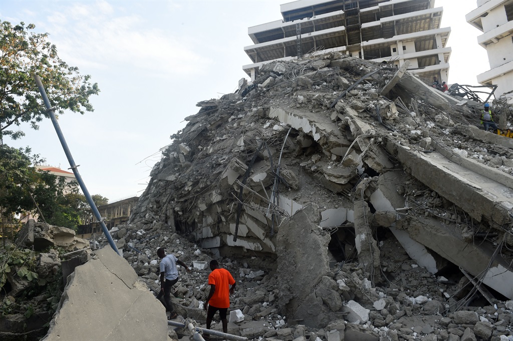 People walk to rescue workers from the rubble of a 21-storey building under construction that collapsed at Ikoyi district of Lagos, on 1 November, 2021. 
