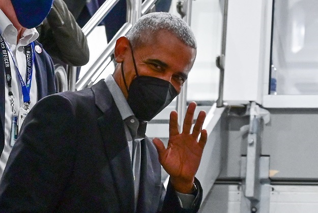 Former US President Barack Obama waves as he walks to a session during the COP26 UN Climate Change Conference. 