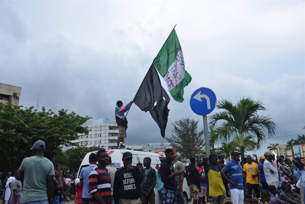 A man stand on a bus display a Nigerian flag as pe