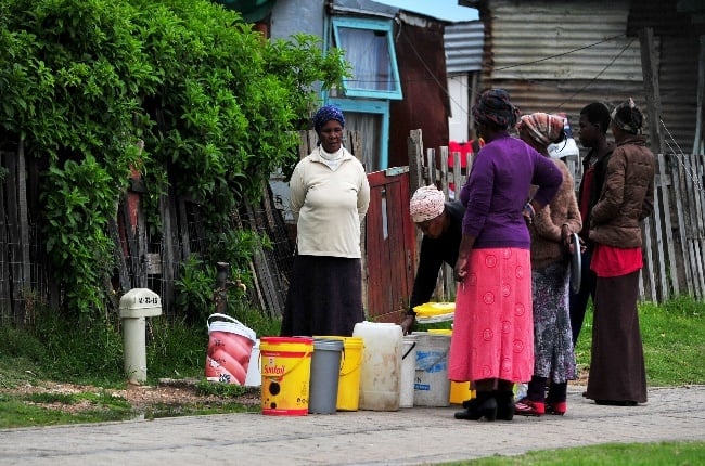 Com­mu­nity members have to wait to collect water from roaming water tankers. (PHOTO: GALLO IMAGES)