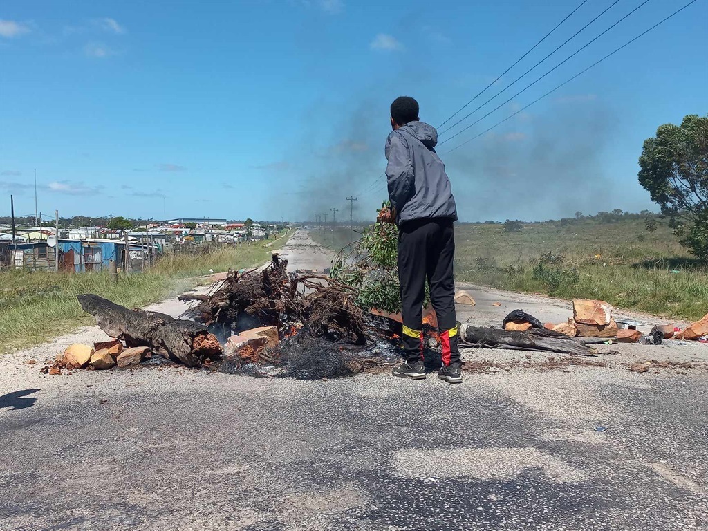 A pupil fans the flames of a road barricade during a scholar transport protest in Gqeberha in January.