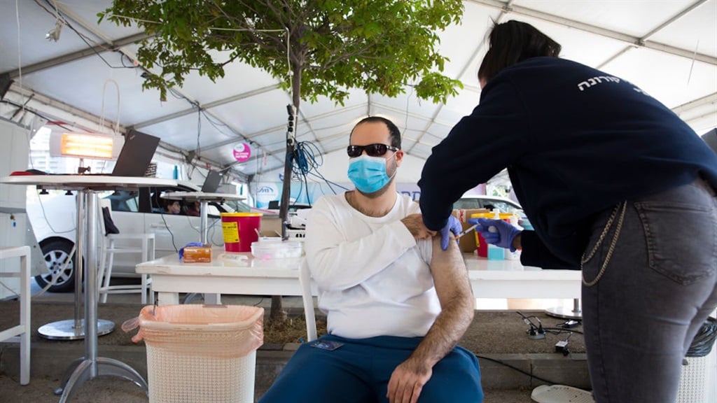 An Israeli man receives a coronavirus vaccine dose from medical staff at a Covid-19 vaccination centre on 31 December 2020 in Haifa, Israel. (Photo by Amir Levy/Getty Images)