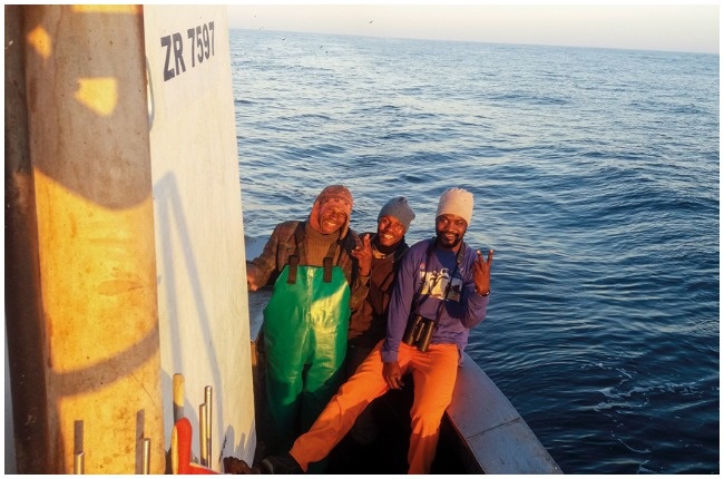 Reason Nyengera (with binoculars) on board a fishing trawler.