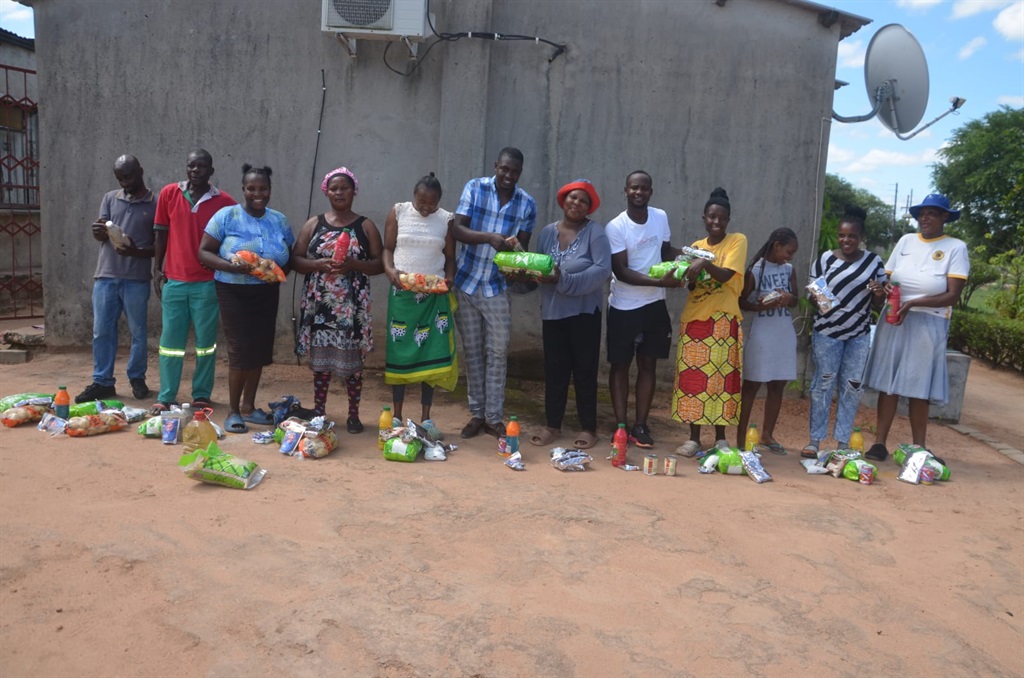 Families receiving food parcels from Dan Kubayi (middle, wearing a check shirt) and his assistant Alex Mashile (fifth from right) in Dumphries Village, Mpumalanga. Photo by Oris Mnisi 