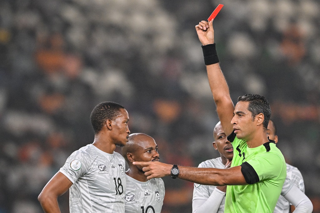 Egyptian referee Amin Omar (R) shows a red card to South Africa's defender #18 Grant Kekana (L) during the Africa Cup of Nations (CAN) 2024 semi-final football match between Nigeria and South Africa at the Stade de la Paix in Bouake on 7 February 2024.  
