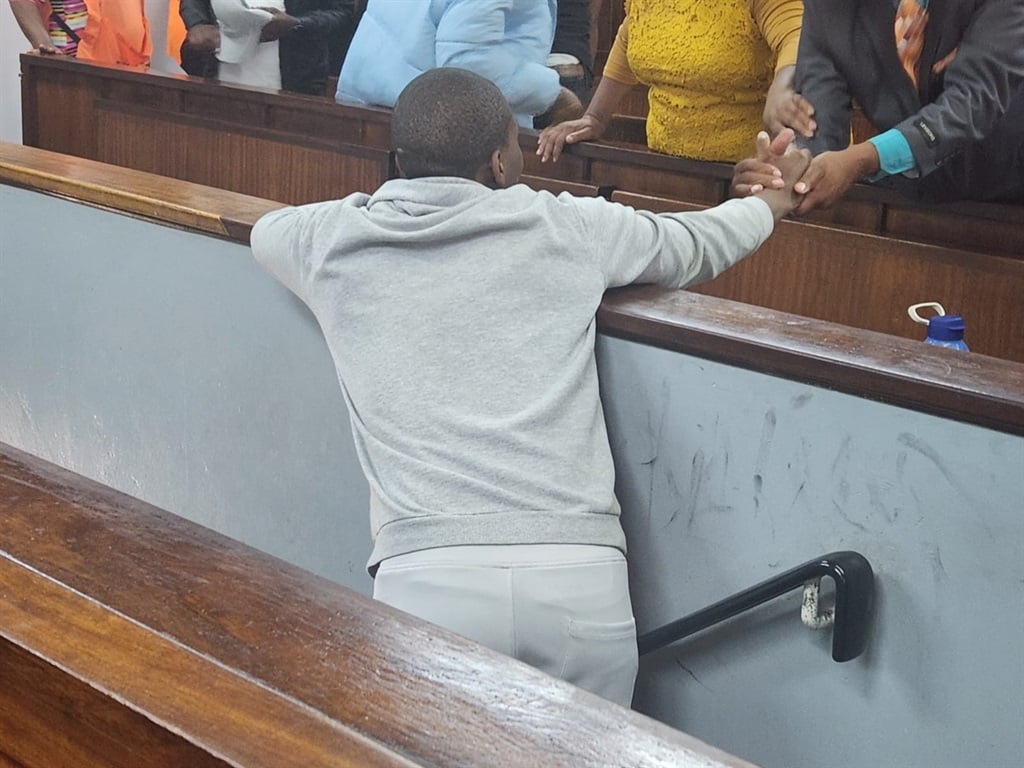 The father of the man accused of the rape and murder of Kirsten Kluyts grabs his son's arm as he is lead into the cells below the Alexandra Magistrate's Court.