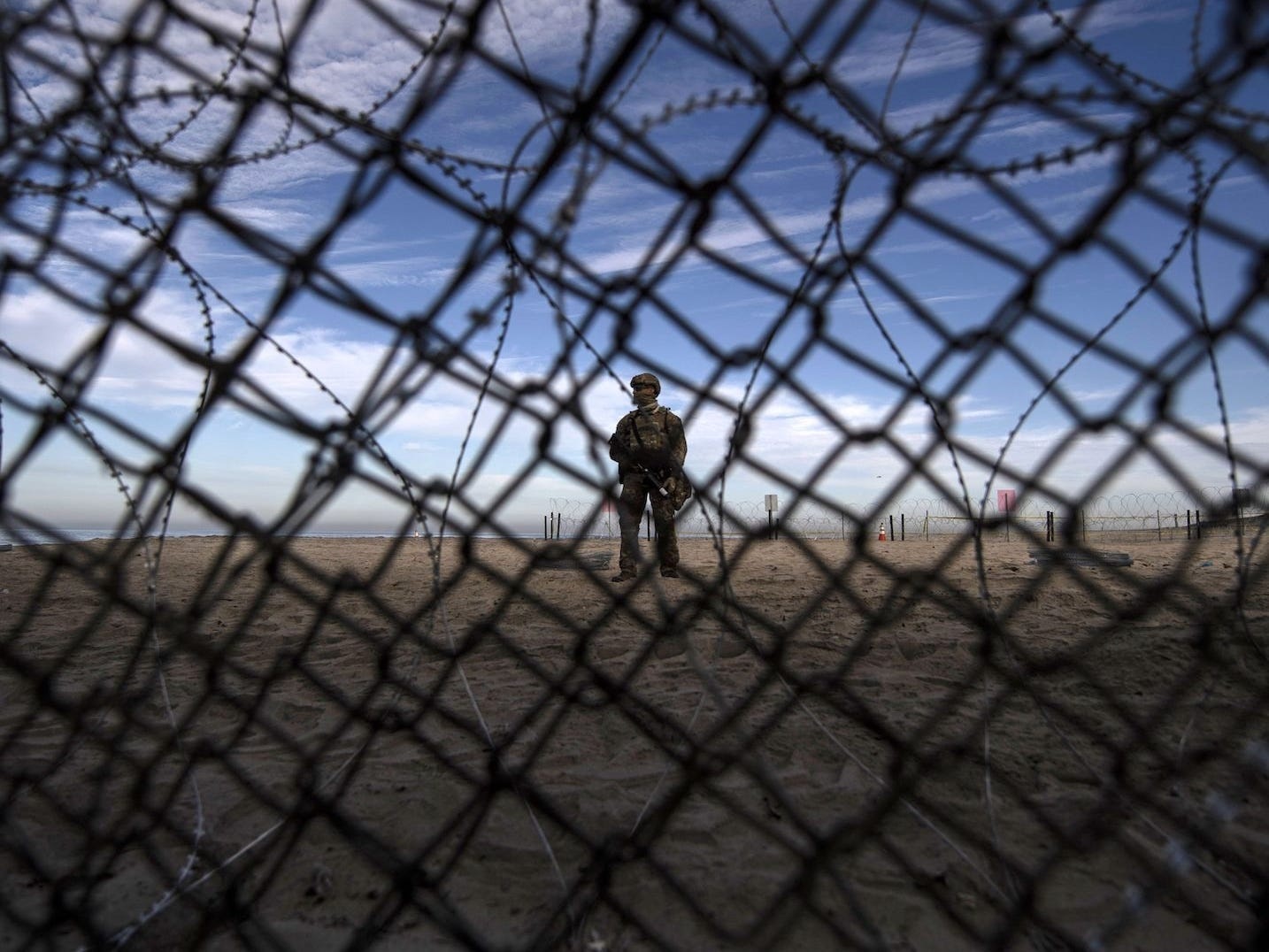 A US Customs and Border Protection agent stands guard on the US side of the US-Mexico border fence.
