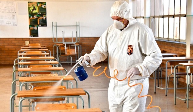 A worker sanitises a classroom.
