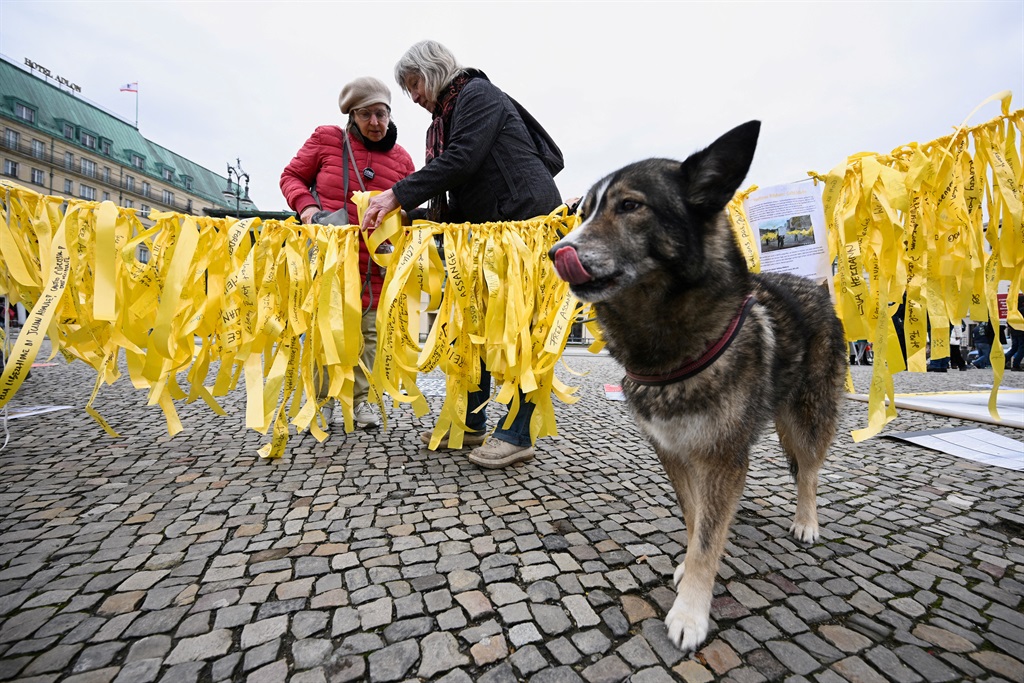 A dog waits as a woman leaves her message on a rib
