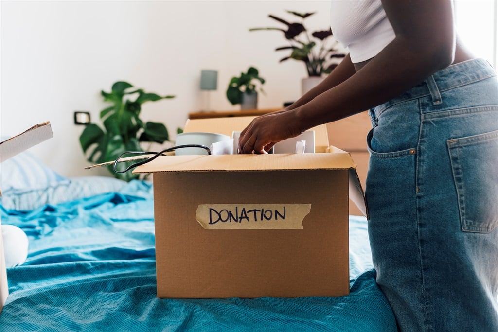 Woman packing donation box on bed at home.